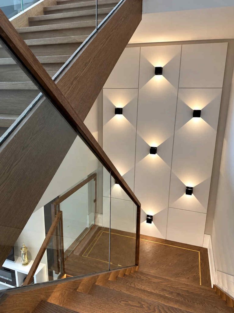 Wooden Staircase With Clear Glass Railings And Warm Lighting